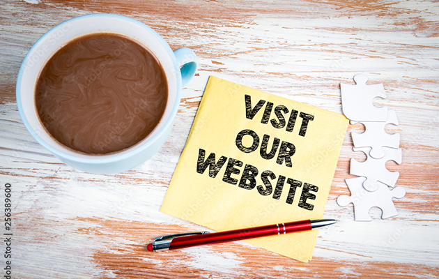 Looking down on a cup of black coffee next to a chalkboard with the words 'visit our website' written on it.